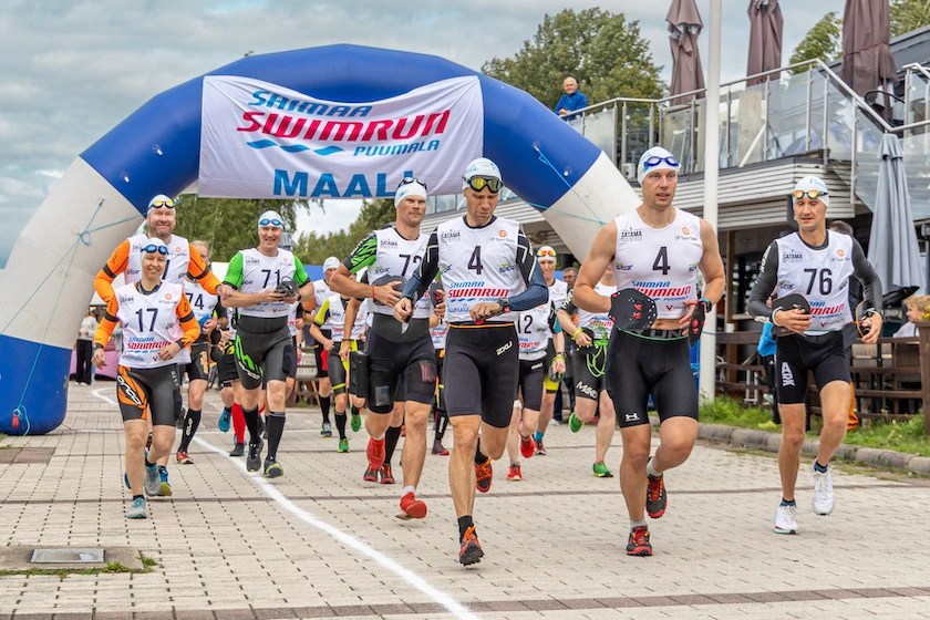 Ryhmä juoksijoita lähtenyt juoksemaan Saimaa SwimRun -tapahtumassa ja taustalla näkyy maalikaari.